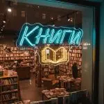 Неоновая вывеска «КНИГИ» с голубо-жёлтой подсветкой и контуром открытой книги