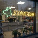 Неоновая вывеска «ЗООМАГАЗИН» с собакой и жёлто-зелёной подсветкой
